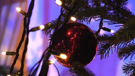 Still-shot-of-close-up-of-a-Christmas-ball-on-a-tree-The-Mansion-House-with-lights-in-the-background