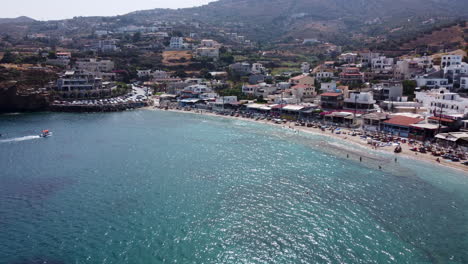 a wide drone shot of the boats and beaches in agia pelagia, a resort town in crete