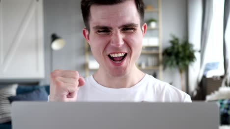 primer plano de un hombre emocionado celebrando el éxito en la computadora portátil