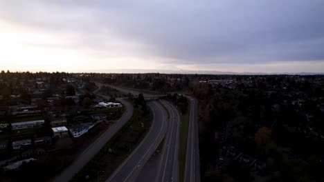 Gloomy-skies-above-a-busy-highway,-Mount-rainier-partially-cloud-shrouded-in-background,-aerial