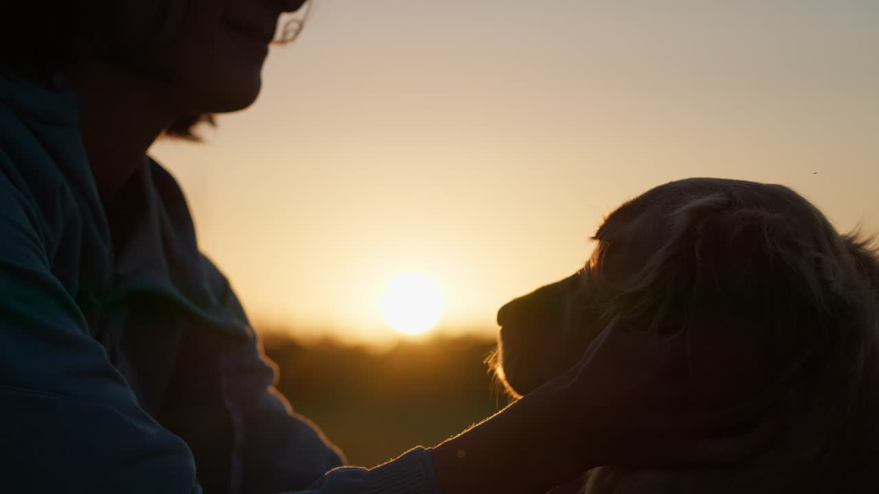 Woman and golden retriever enjoy sunset together, sharing a warm moment