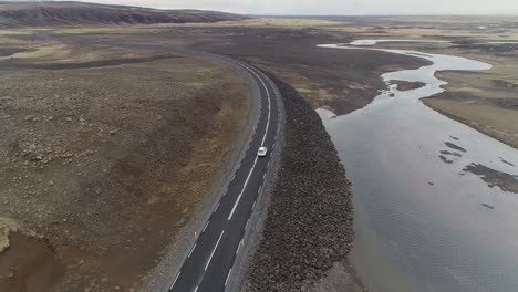 Aerial-Tilt-Over-of-Car-driving-between-a-Mountain-and-a-River