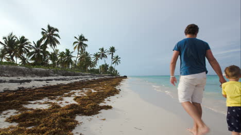 Family-of-three-walking-along-the-beach-in-tropics