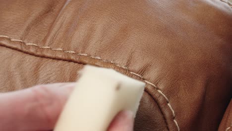 hands delicately dab matching paint with sponge to erase sofa scratch completely