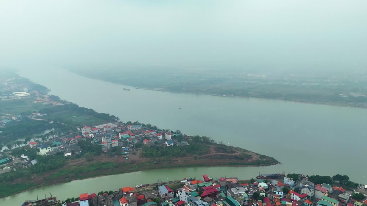 Wide drone shot of the outskirts of Hanoi, Vietnam, with the river and residential buildings visible. Extreme Pollution