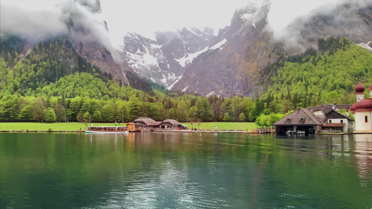 Splendido paesaggio lacustre alpino con barche di legno e baite