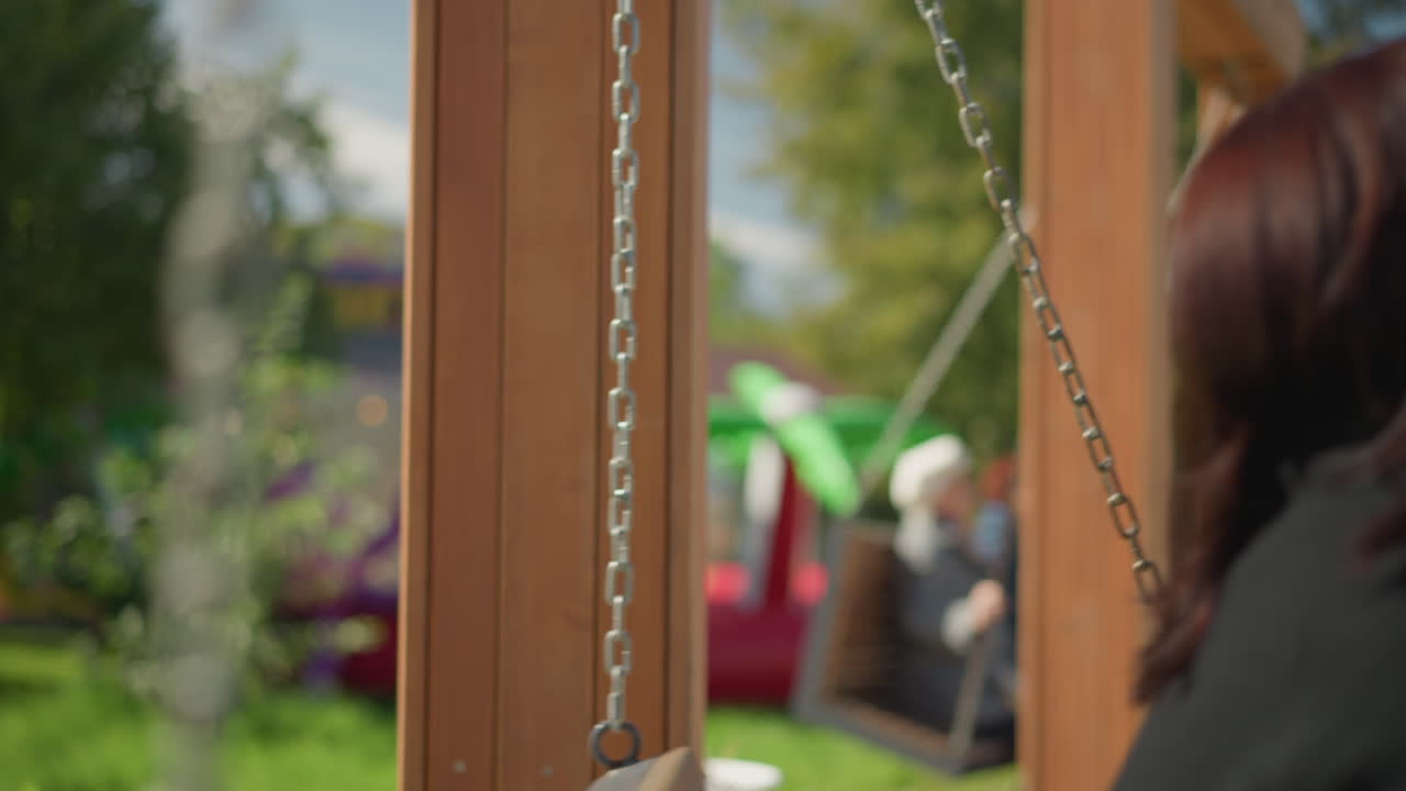 스하는 동안 머리카락을 조정하는 여자의 클로즈업, 태양빛이 그녀에 반사되고 배경에 울창한 초록색, 다른 사람들이 스하는 흐릿한 시각