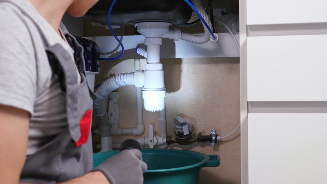 hombre parpadea la antorcha mirando el agua que se filtra de la trampa de residuos