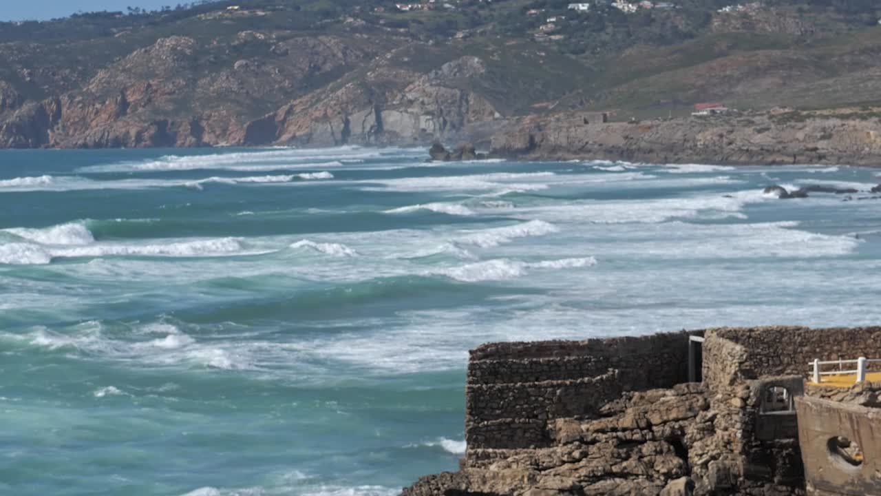 SLOW MO azure waves with mountains in the background, Cape Roca, Portugal