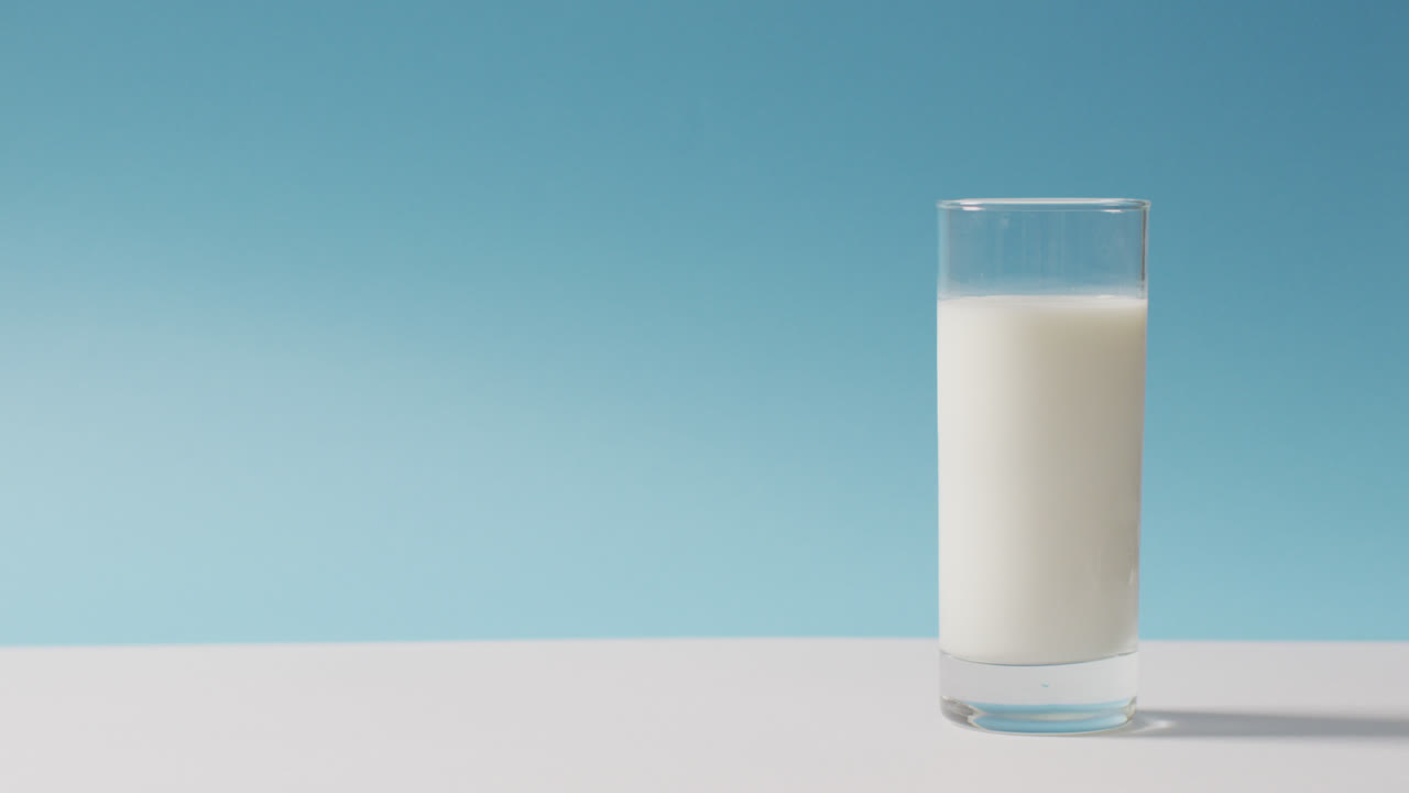 video de un vaso de leche fresca sobre un fondo azul