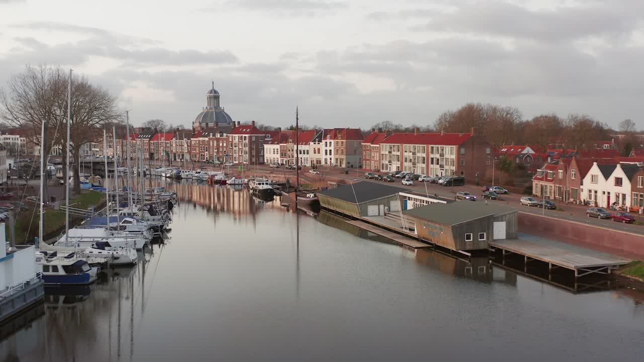 Revealing drone shot of a small marina in a city, surrounded by historical residential buildings