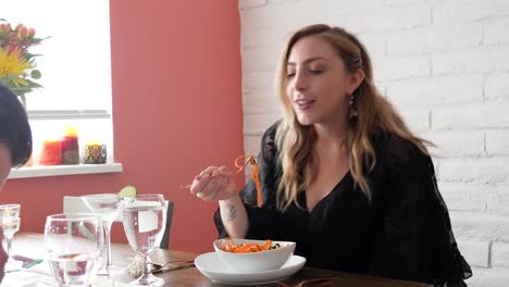 young woman eating vegan linguine, italian food pasta dish orange in color and served as an appetizer for dinner or lunch in a home dining room.