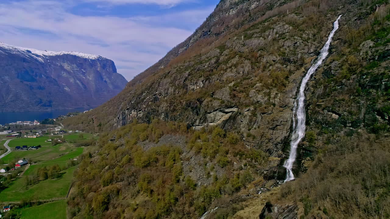 toma aérea de drones en movimiento hacia adelante de majestuosas montañas con cascada kjelfossen cerca del pueblo de gudvangen, municipio de aurland, condado de vestland, noruega durante el día