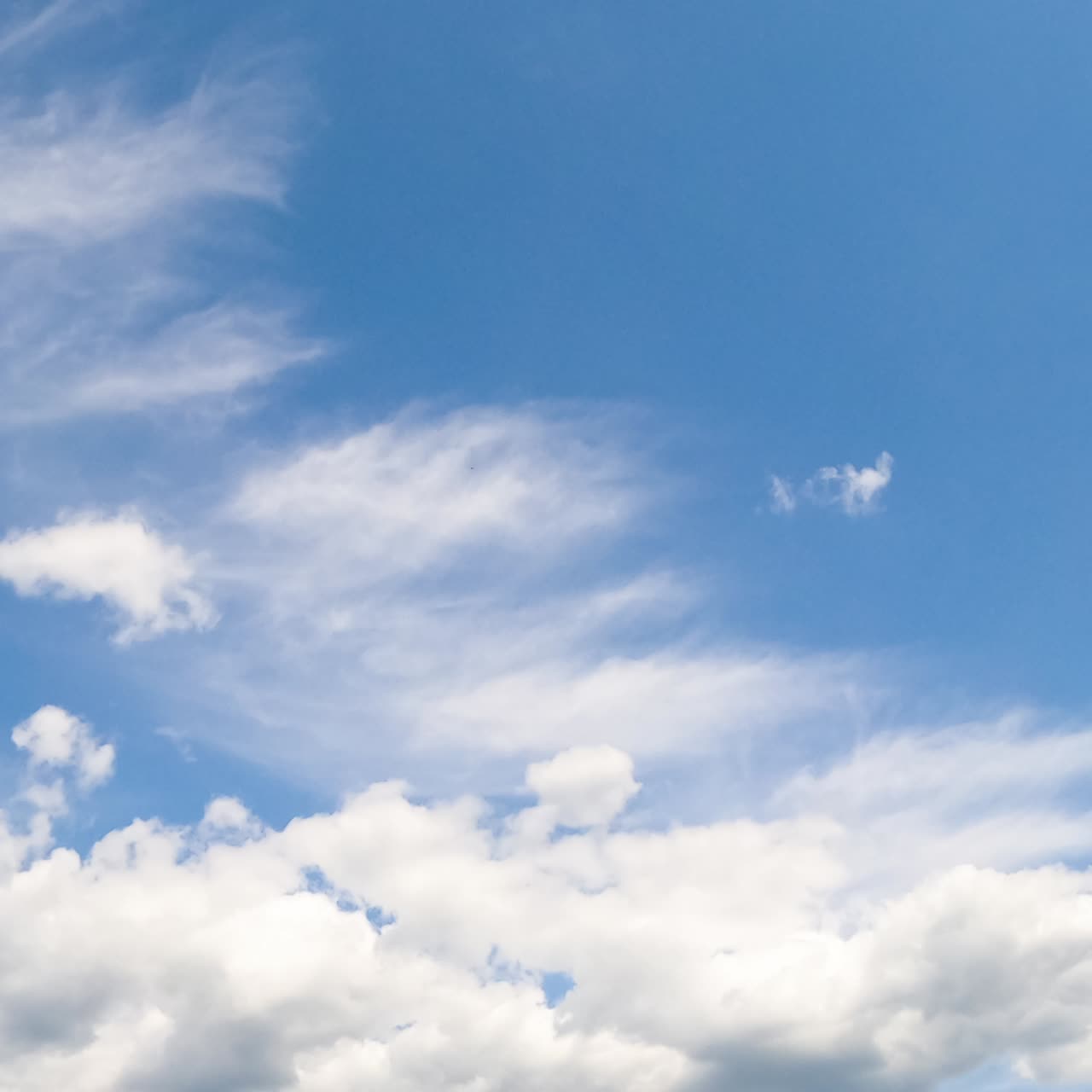 Light blue summer sky with fluffy soft clouds. White cloudscape formation from low angle view
