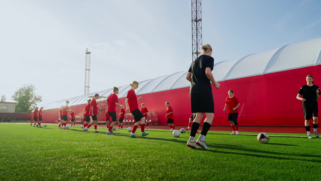 Ungdomsfotballag øver på dribleøvelser på en utendørs bane