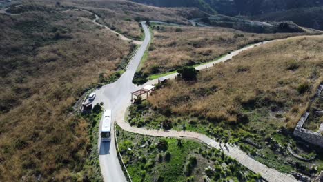 Aerial-of-a-White-Bus-Driving-on-an-Empty-Road-through-the-Mountains-in-Fall