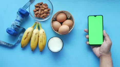 smart phone with empty screen , eggs , milk and almond nut in table