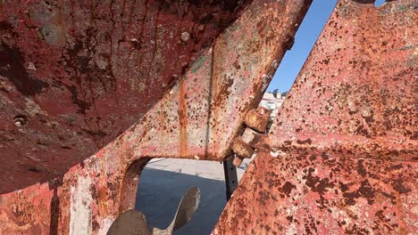 hélice del motor y timón de metal grueso y oxidado de un viejo barco de pesca varado en el puerto para ser reparado y sintonizado, día soleado, primer plano viajando hacia abajo