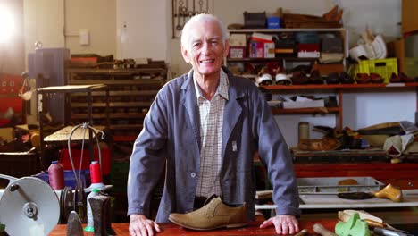 portrait of smiling shoemaker standing in workshop