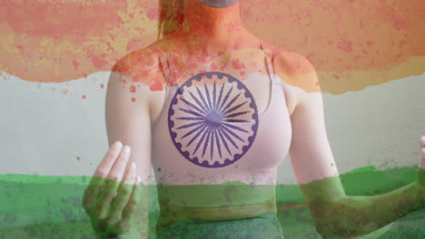 Animation-of-woman-wearing-face-mask-practicing-yoga-over-indian-flag