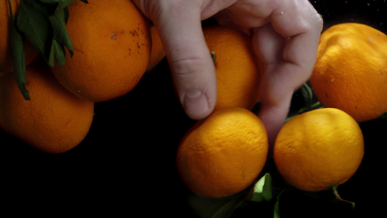 Man's hand under the water with fresh tangerines.