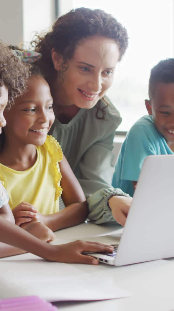 Video of happy caucasian female teacher explaining lesson on laptop to diverse pupils