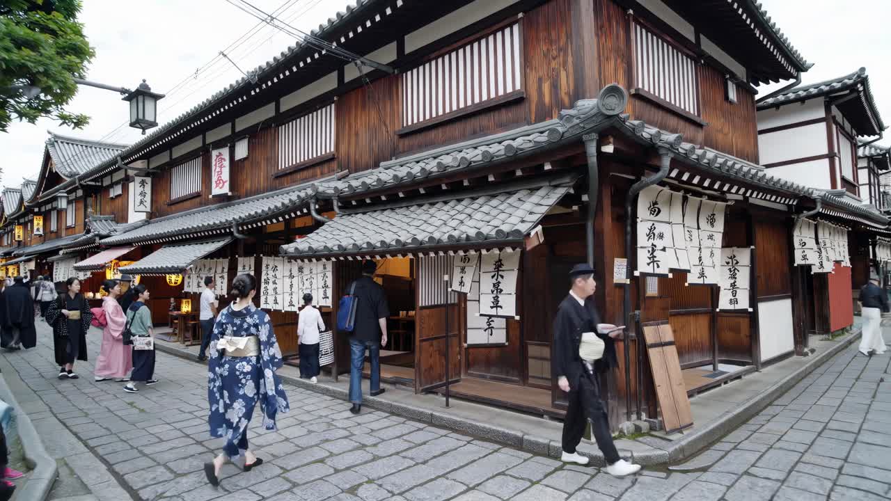 Street-level video shot of a traditional Japanese market with wooden buildings and people