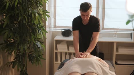 primer plano de las manos del masajista vertiendo aceite aromático en la espalda de la mujer. la masajista se prepara para hacer el procedimiento de spa oriental para el tratamiento relajante. el terapeuta haciendo masaje de aceite de aromaterapia en el cuerpo de la mujer