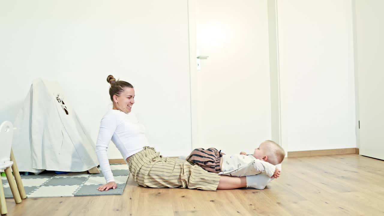 Happy mother amuses her little son, hugs the child. Family games with child, leisure time, motherhood in joy, mother plays active funny game with son