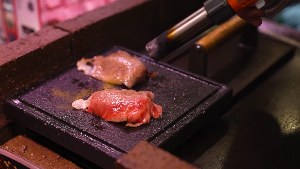 Cooking steak on a sizzling hot plate with tongs