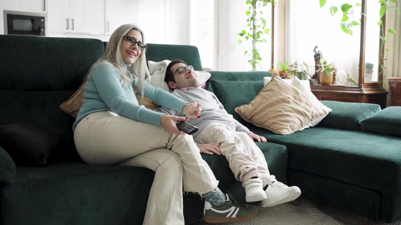 Moden kvinde og søn slapper af på sofaen derhjemme