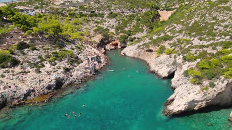 drone view of the rocky coastline with people swimming in a clear water