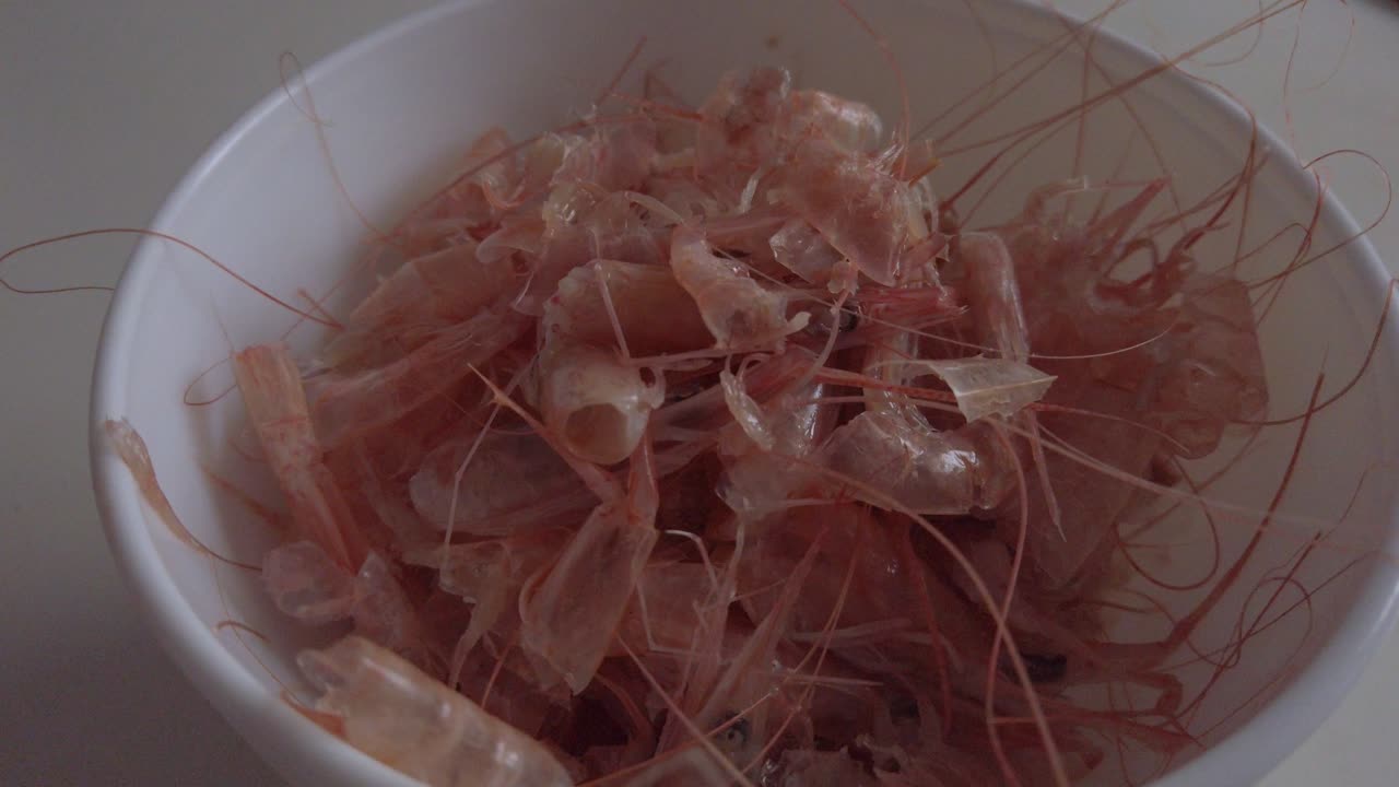 cáscaras de gambas rosas peladas descartadas en un tazón blanco, empujar hacia adentro