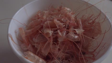 cáscaras de gambas rosas peladas descartadas en un tazón blanco, empujar hacia adentro