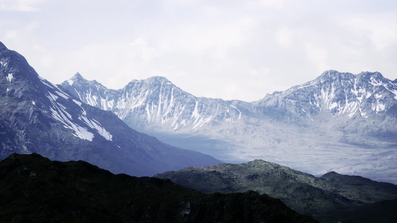 Majestic snow capped mountains rise under a cloudy sky in the afternoon ...