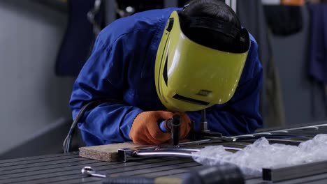 uomo che indossa una maschera di saldatura in un laboratorio. i lavoratori del metallo usano il lavoro manuale. saldatore esperto. saldatore sta saldando i tubi in acciaio inossidabile in fabbrica. saldatore parte industriale in fabbrica