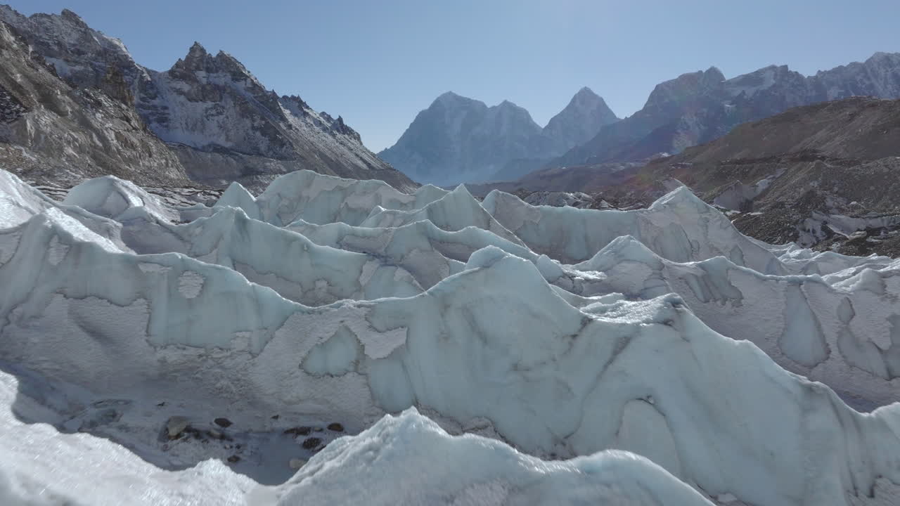 Droneopptak av et skinnende istårn på Khumbu-breen, etterfulgt av den omkringliggende tørre fjellkjeden i Everest-regionen, Himalaya, Nepal.