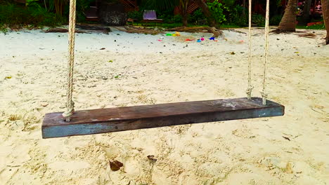 Close-up-shot-of-an-empty-swing-with-a-rope-and-white-sands-on-foreground