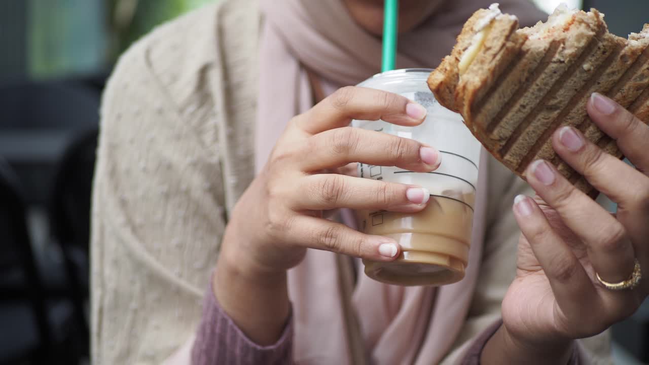 mujer comiendo un sándwich y bebiendo café