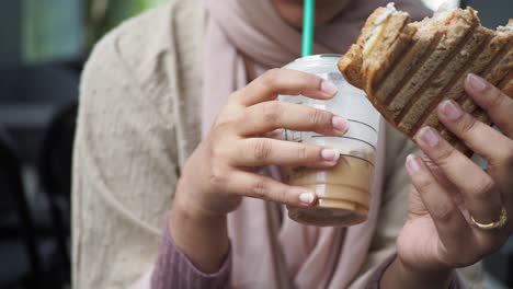 woman eating a sandwich and drinking coffee