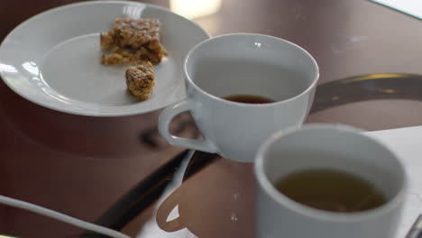 close up of hot drinks in cups on table at home with snack and computer connection cables