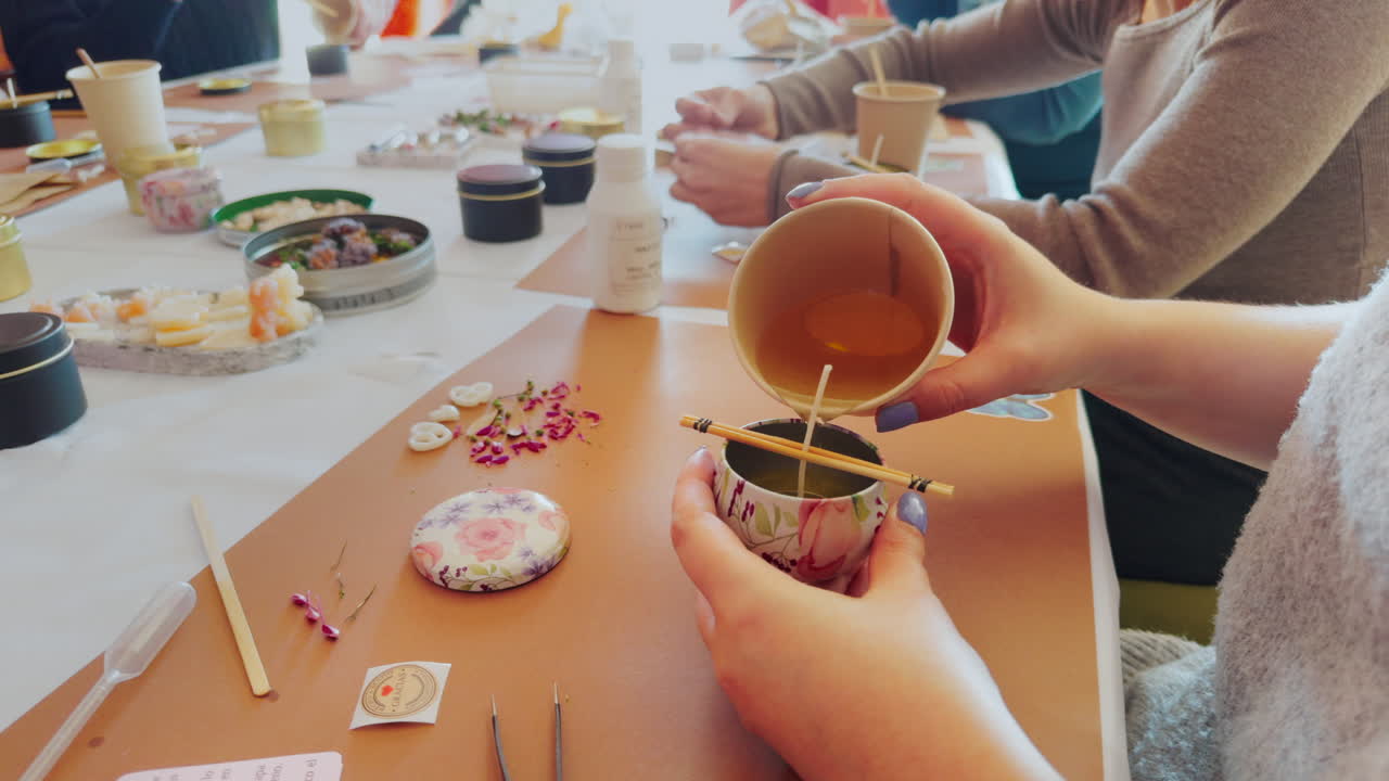 Woman placing melted candle wax in container during candle creation workshop