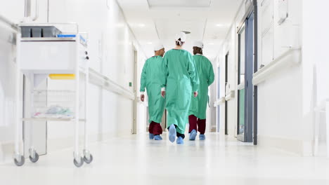 diverse male and female surgeons wearing surgical gowns walking in corridor at hospital, slow motion