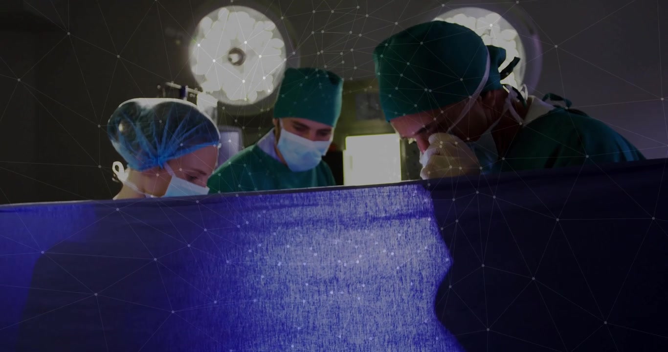 Con le luci operatorie che si abbassano, l'equipe chirurgica chinata sul telo sterile che prepara l'intervento chirurgico.