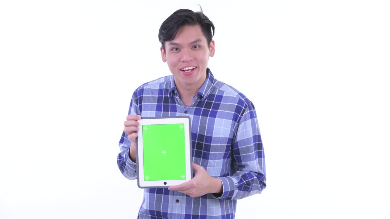 젊은 잘생긴 아시아 남자의 초상화로 백색 배경에 고립된 녹색 화면의 노트북을 보여줍니다.