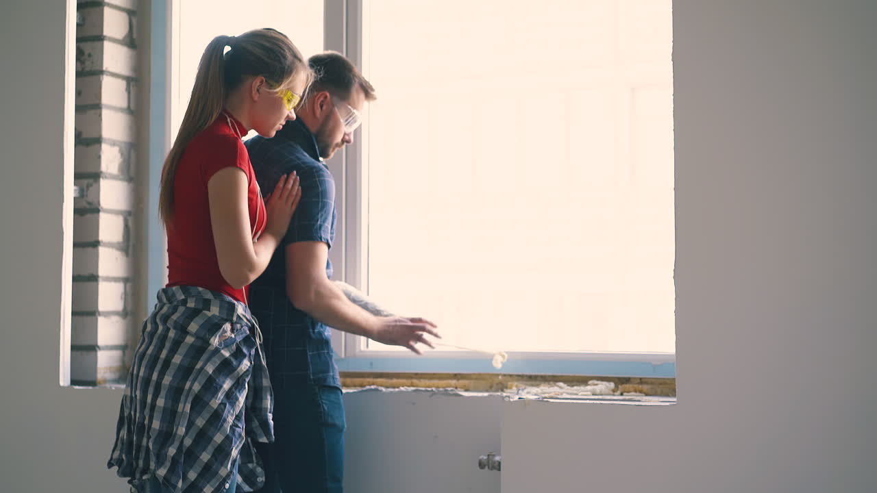 woman hugs husband applying spray foam insulation on sill