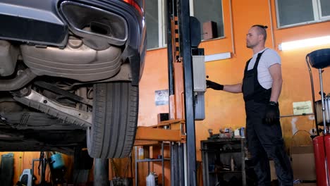mechanic working with a car on a lift in an auto repair shop