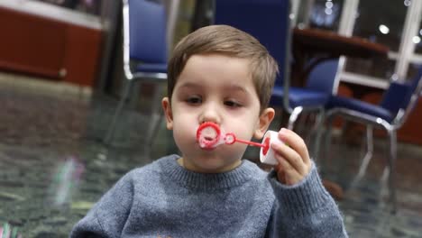 video de un niño soplando burbujas de jabón y disfrutando del juguete