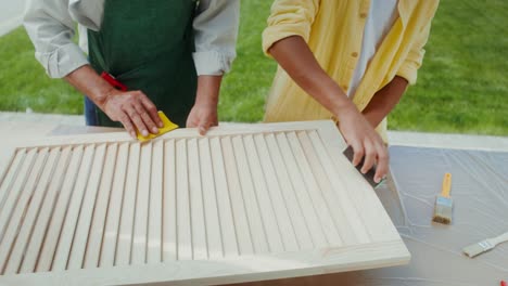 dos personas arenando persianas de madera