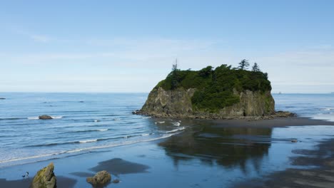 drone se eleva para revelar el océano pacífico detrás de una gran roca en ruby beach en la península olímpica de washington